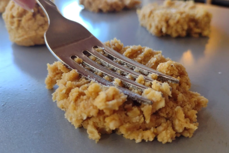 Pressing a sugared fork onto the cookies to create a criss-cross shape